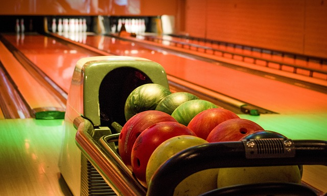En bowlinghall, med klot i olika färger ligger på rad. I bakgrunden syns käglorna och banorna.
