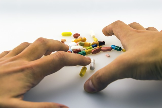 Medicinkapslar i olika färger på ett bord. Två händer som i luften precis ovanför.