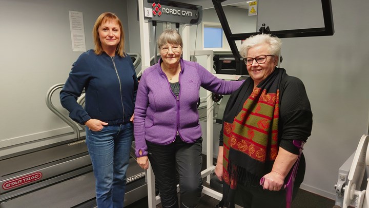 Tre personer står framför träningsmaskiner på ett gym.