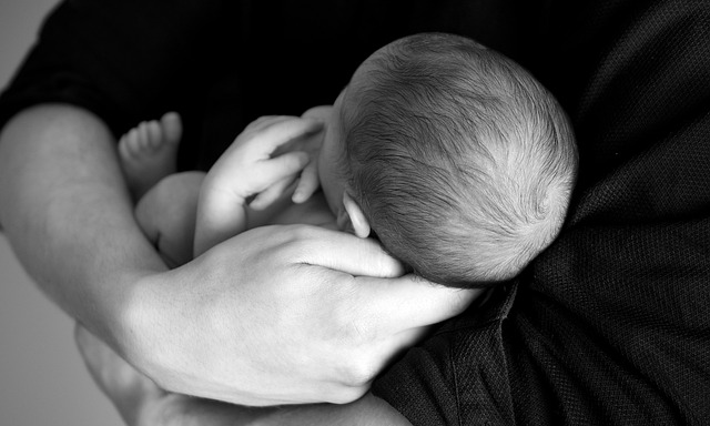 Baby i en famn, svartvit bild.