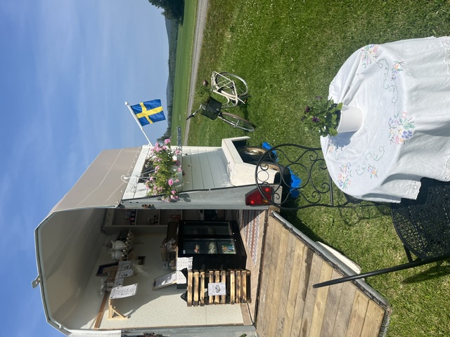 Gårdsvagn med fasadflagga. Bord med vit duk framför.
