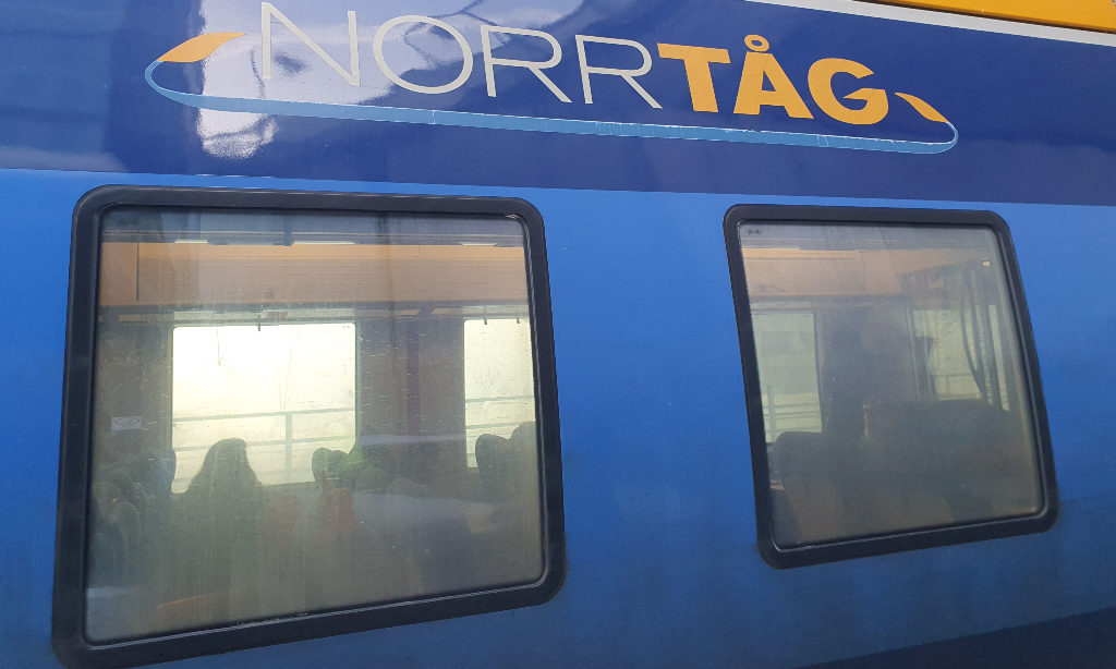 Norrtågs blå tåg med texten Norrtåg i vitt och gult. Fönstren i närbild. 
