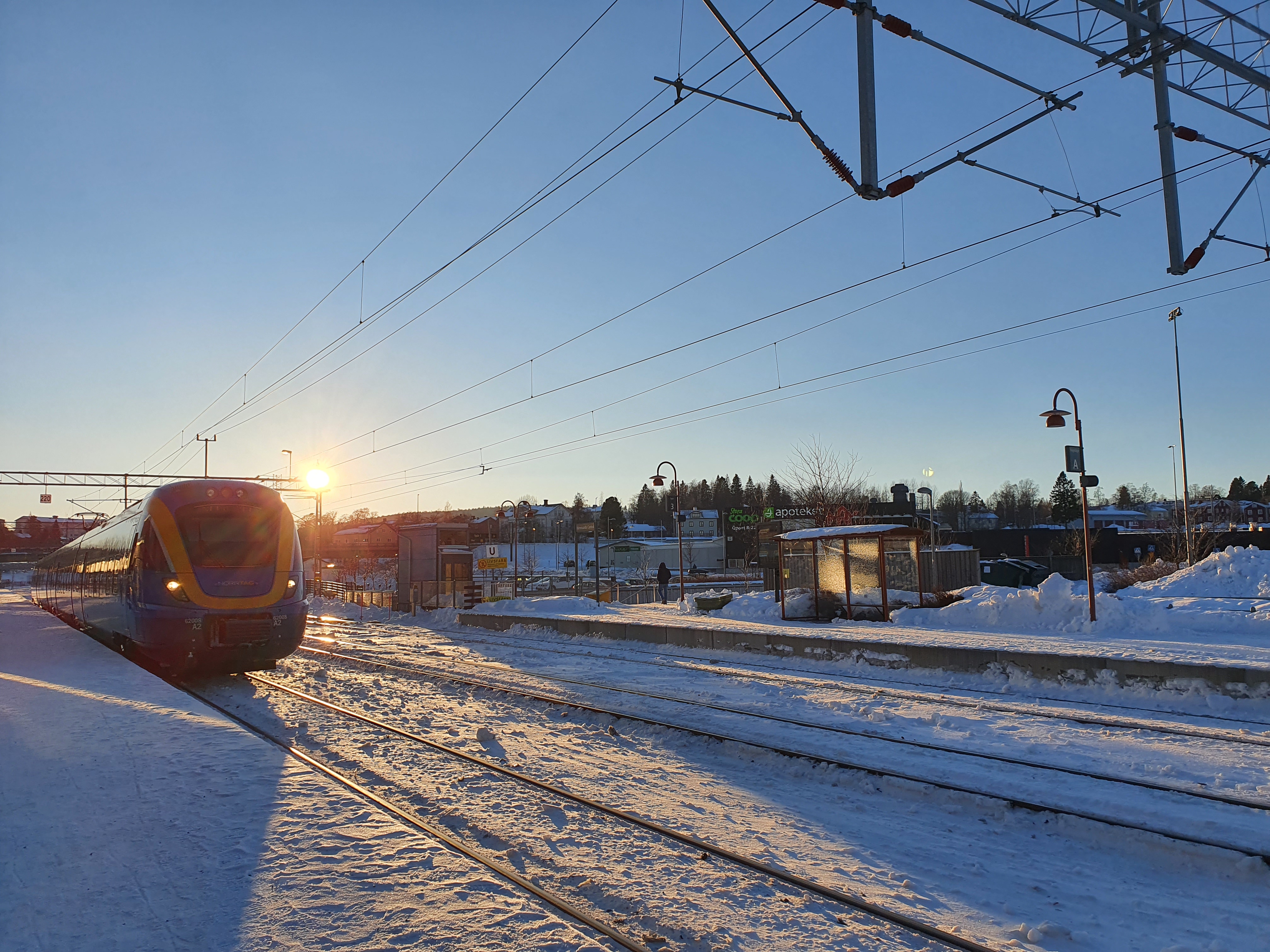 Tåg ankommer till perrong. Det är vinter.