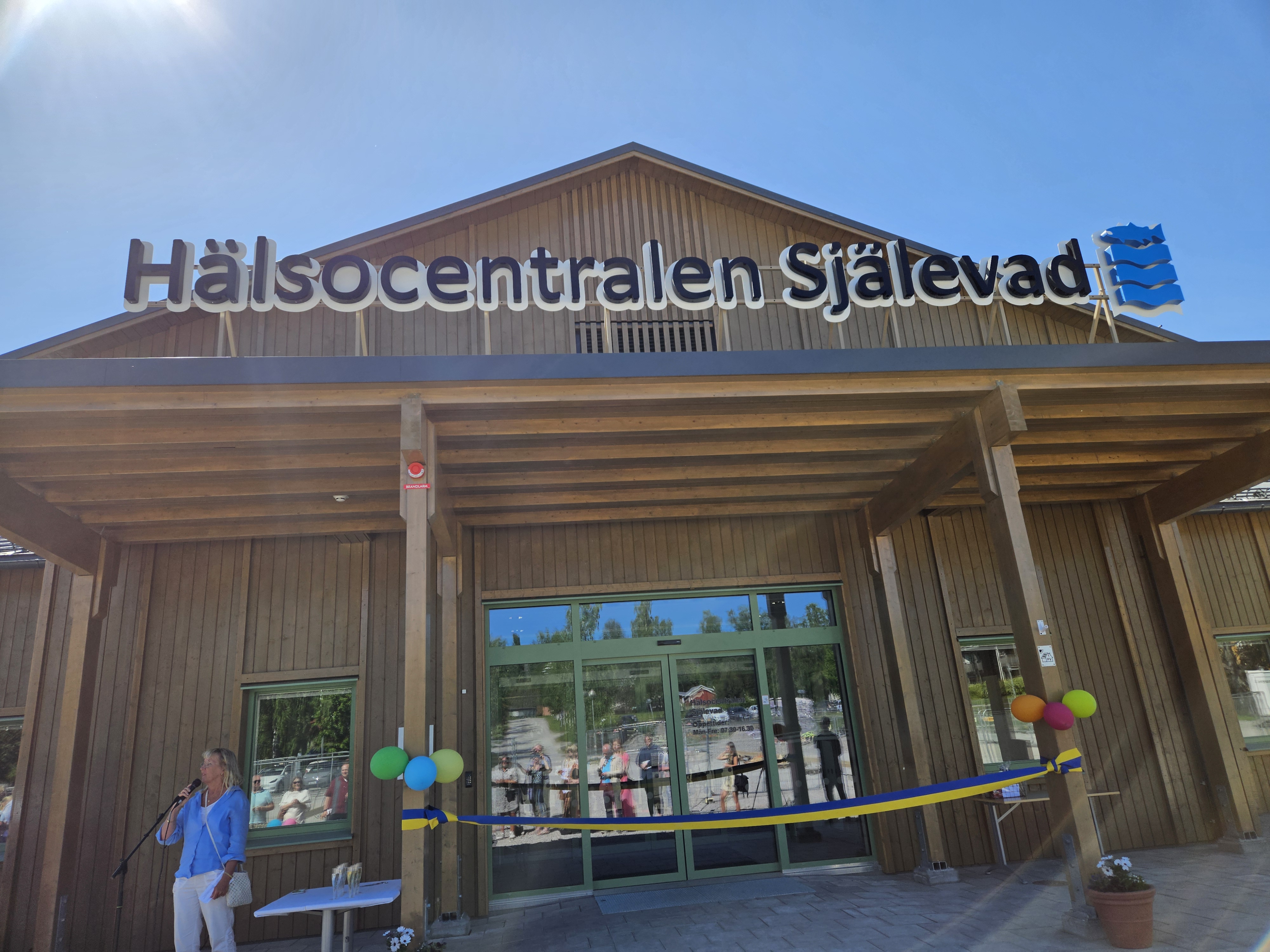 Hälsocentralen Själevads entré på invigningsdagen. Ballonger och bandet i gult och blått som klipptes av.