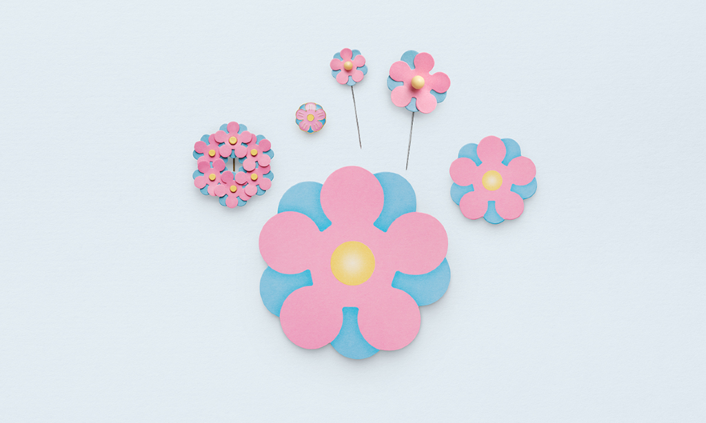 Majblomman i olika utföranden/pins. Årets är ljusblå och ljusrosa.