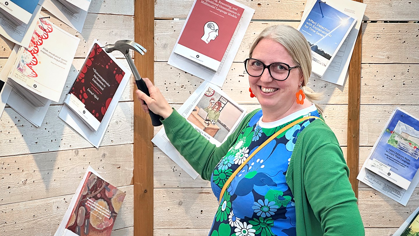 Emma spikar upp sin avhandling på trävägg, bland andra avhandlingar.