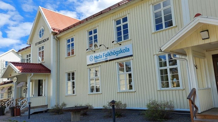 Framsidan på Hola folkhögskola. Det är en träbyggnad med vaniljfärg.