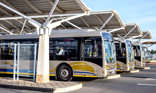 Vita bussar med gula fält uppradade under tak i i bussterminal